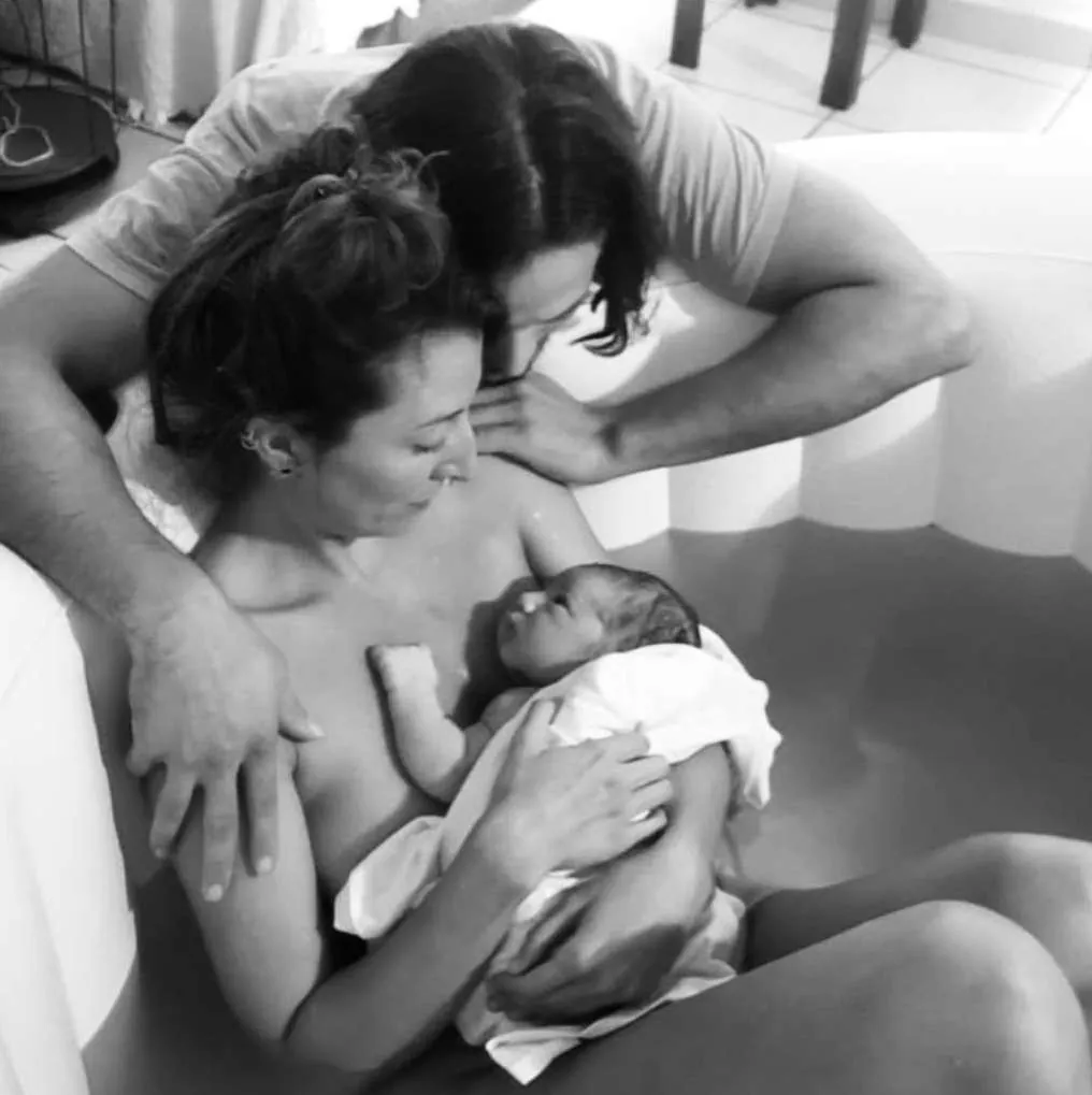 Madre con su recién nacido en la tina de parto, blanco y negro